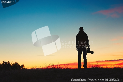 Image of Silhouette of young photographer is enjoying sun. Photographer at the sunrise