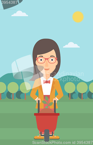 Image of Woman with plant and wheelbarrow.