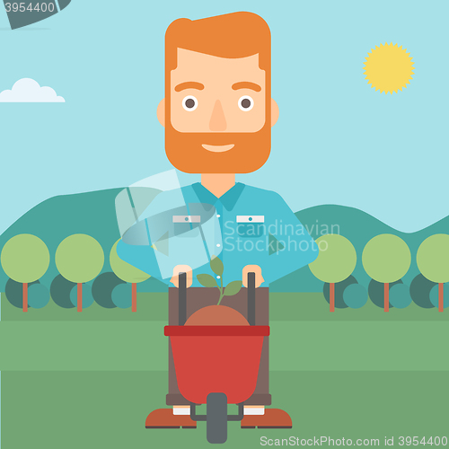 Image of Man with plant and wheelbarrow.