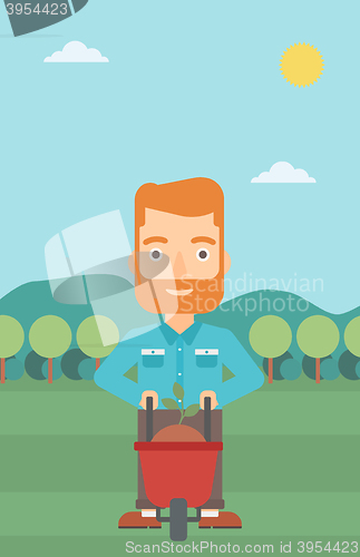 Image of Man with plant and wheelbarrow.