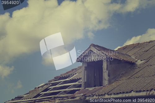 Image of Old tile roof with holes and sky with clouds