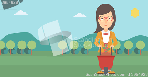 Image of Woman with plant and wheelbarrow.