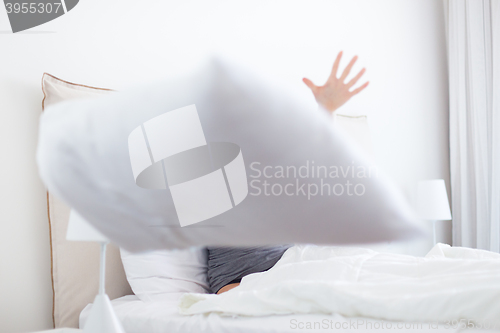 Image of Woman throwing white pillow at camera.