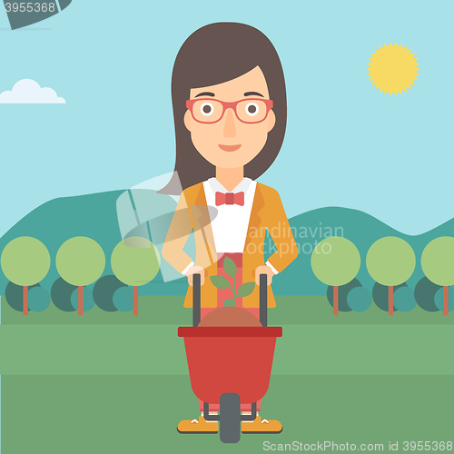 Image of Woman with plant and wheelbarrow.