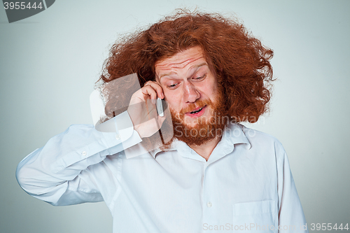 Image of Portrait of puzzled man talking on the phone  a gray background