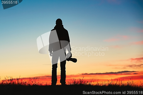 Image of Silhouette of young photographer is enjoying sun. Photographer at the sunrise