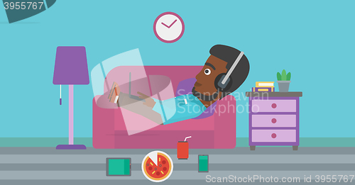 Image of Man lying on sofa with many gadgets.