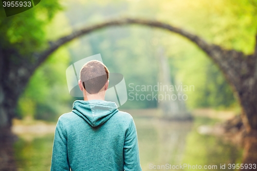 Image of Pensive man is looking at the old bridge