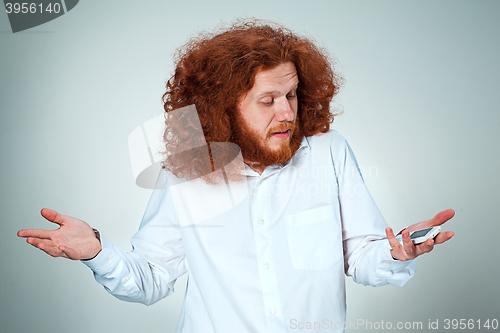 Image of Portrait of puzzled man talking on the phone  a gray background