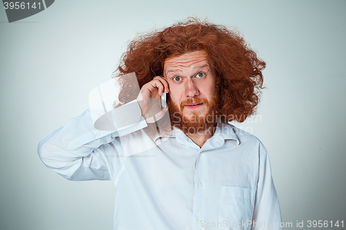 Image of Portrait of puzzled man talking on the phone  a gray background