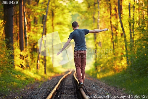 Image of Young man walking on the railway