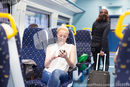 Image of Woman using mobile phone while travelling by train.