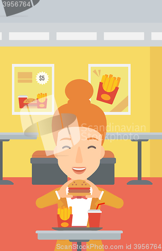 Image of Woman eating hamburger. 