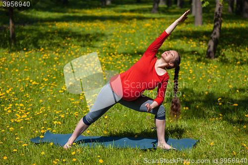 Image of Pregnant woman doing asana Utthita parsvakonasana outdoors