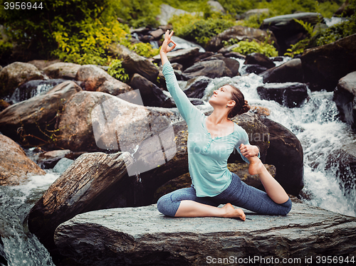 Image of Sorty fit woman doing yoga asana outdoors at tropical waterfall