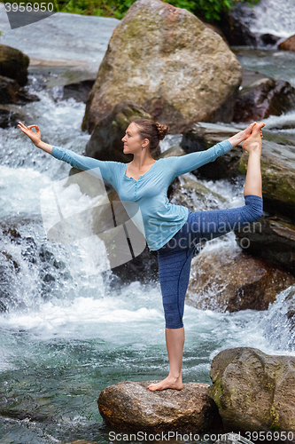 Image of Woman doing yoga asana Natarajasana outdoors at waterfall