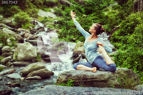 Image of Sorty fit woman doing yoga asana outdoors at tropical waterfall
