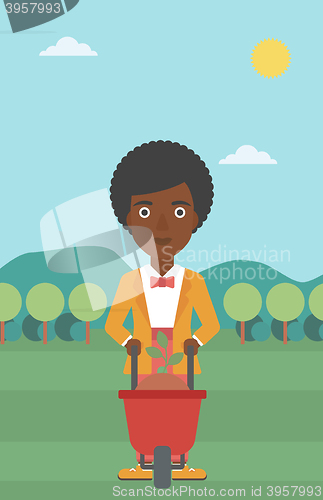 Image of Woman with plant and wheelbarrow.