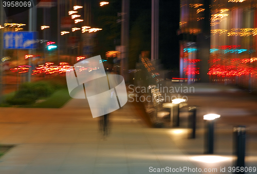 Image of Abstract of woman walking in city at night