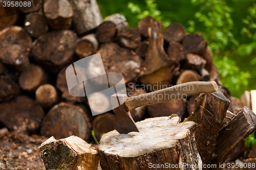 Image of Old ax on log and firewood in the background