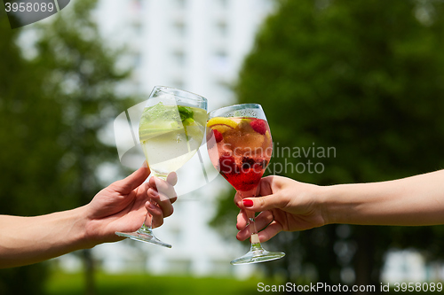 Image of Hand holding glasses cocktail clinking together at outdoor.