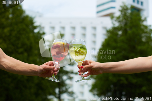 Image of Hand holding glasses cocktail clinking together at outdoor.