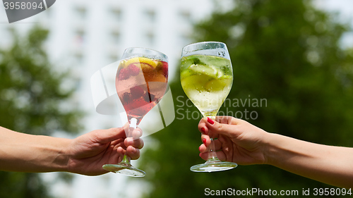 Image of Hand holding glasses cocktail clinking together at outdoor.