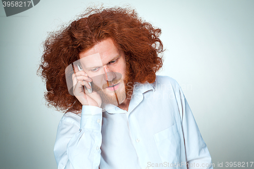 Image of Portrait of puzzled man talking on the phone a gray background