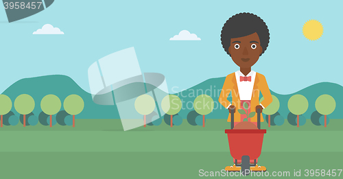 Image of Woman with plant and wheelbarrow.