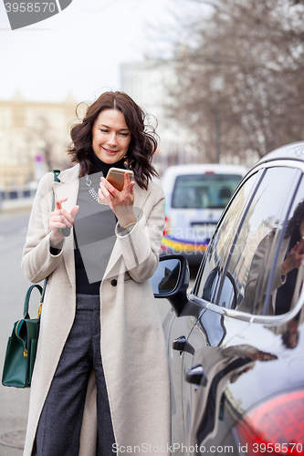 Image of smiling middle aged brunette with smartphone