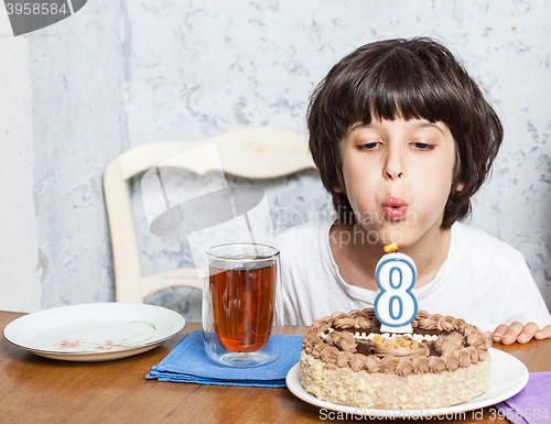 Image of boy blowing out candles on birthday cake