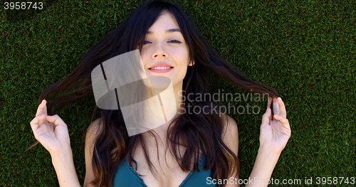 Image of Pretty woman with long brown hair lays in grass