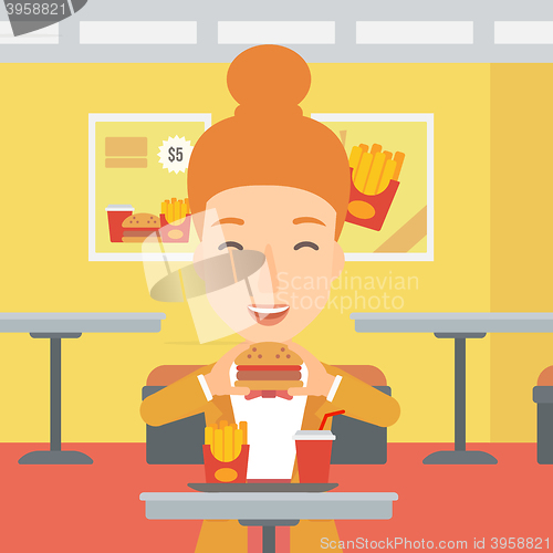 Image of Woman eating hamburger. 