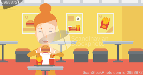 Image of Woman eating hamburger. 