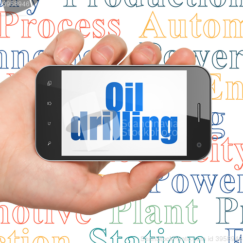 Image of Industry concept: Hand Holding Smartphone with Oil Drilling on display