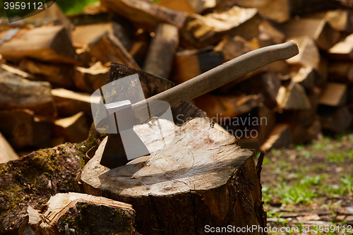 Image of Old ax on log and firewood in the background