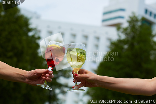 Image of Hand holding glasses cocktail clinking together at outdoor.