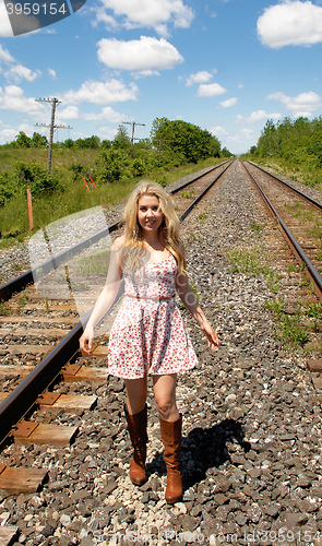 Image of Young woman walking on railroad track's.