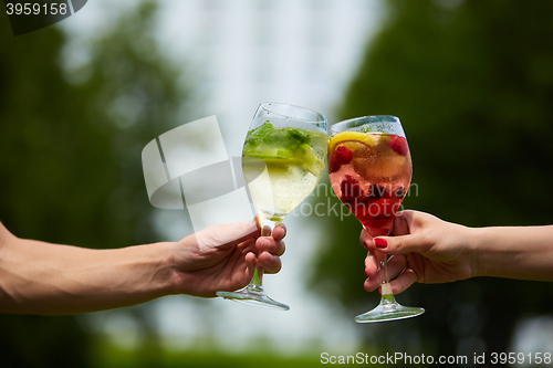 Image of Hand holding glasses cocktail clinking together at outdoor.