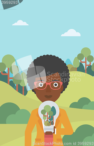 Image of Woman with lightbulb and trees inside.