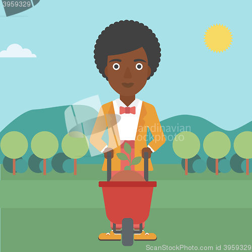 Image of Woman with plant and wheelbarrow.