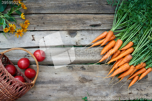 Image of Fresh carrots bunch and tomatoes on rustic wooden background