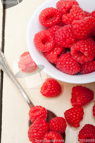 Image of bunch of fresh raspberry on a bowl and white table