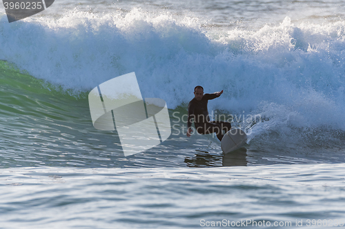 Image of Long boarder surfing the waves at sunset