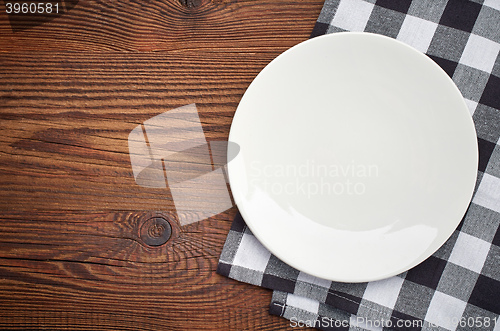 Image of napkin and white plate on wooden table