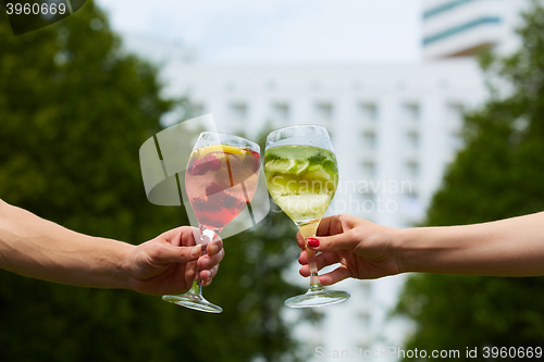 Image of Hand holding glasses cocktail clinking together at outdoor.