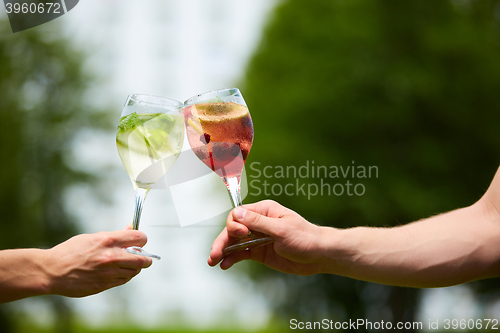 Image of Hand holding glasses cocktail clinking together at outdoor.