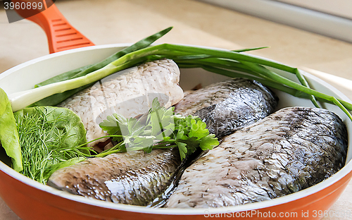 Image of Fish and components for her preparation in a large skillet.