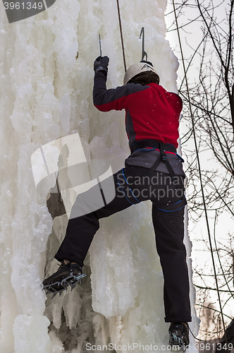 Image of Man climbs upward on ice climbing competition