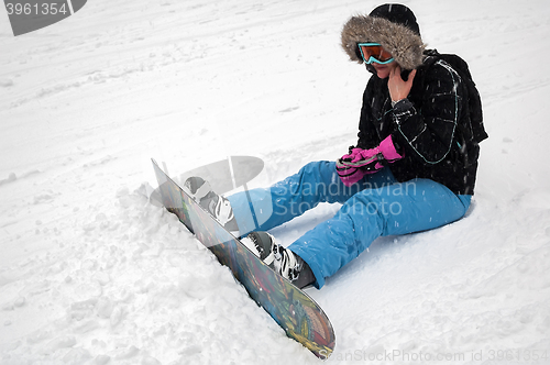 Image of Woman with snowboard rests on snow